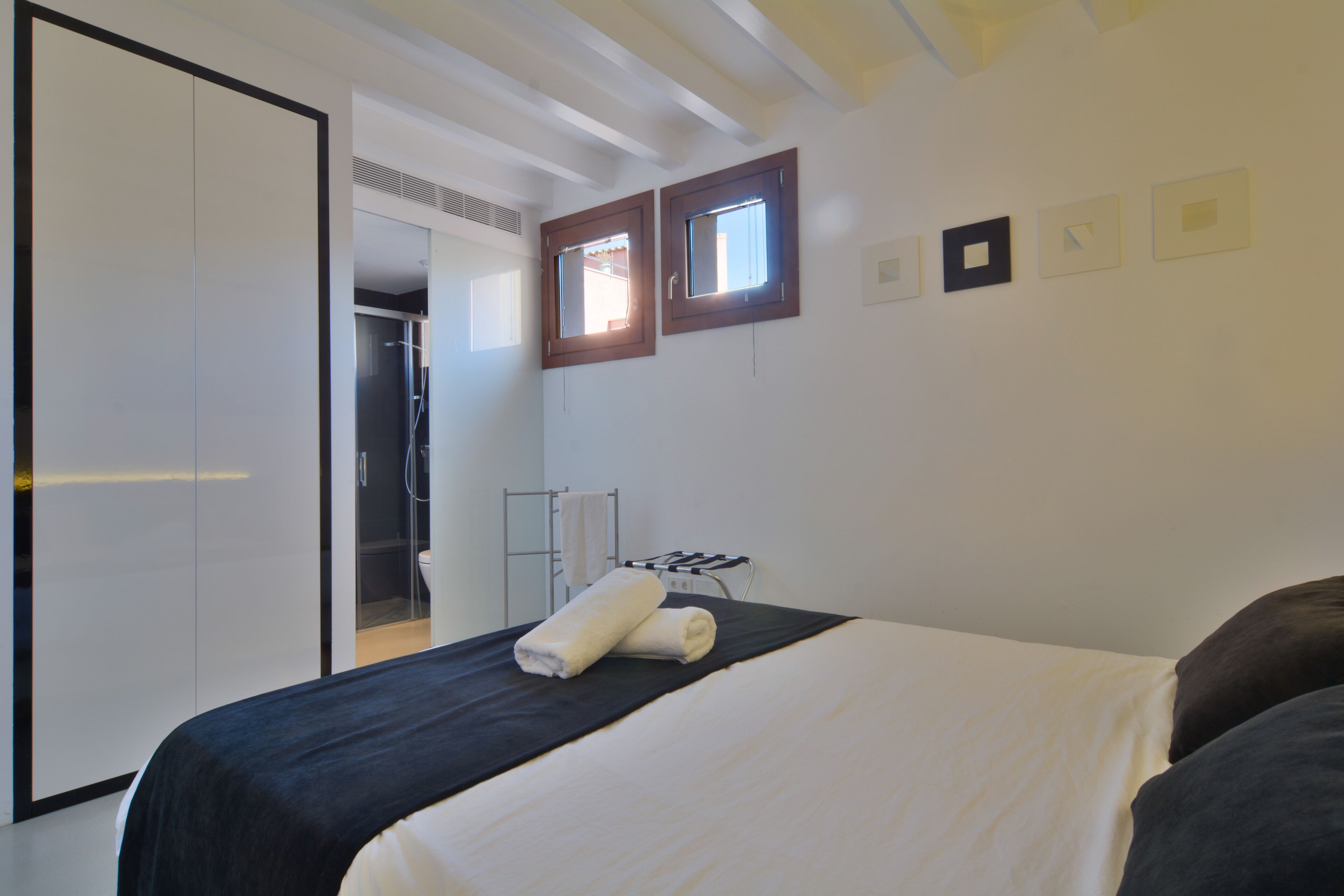 A hotel room with a bed, a wardrobe, a bathroom, and a small window.