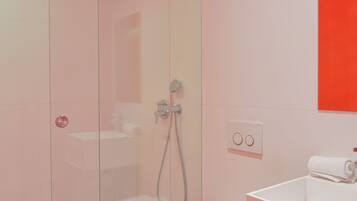 A modern bathroom with a glass shower enclosure, a white toilet, and a sink with a mirror above it.