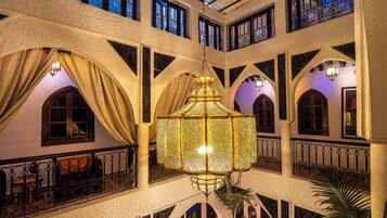 A multi-level atrium with ornate iron railings, a central hanging lantern, and multiple arched windows.