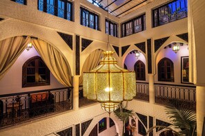 A multi-level atrium with ornate iron railings, a central hanging lantern, and multiple arched windows. - Riad Balkisse (Marrakech)
