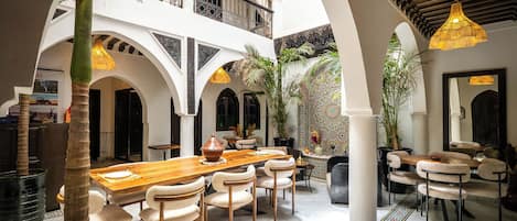 A spacious interior with a high ceiling, multiple dining areas, and a central courtyard with plants.