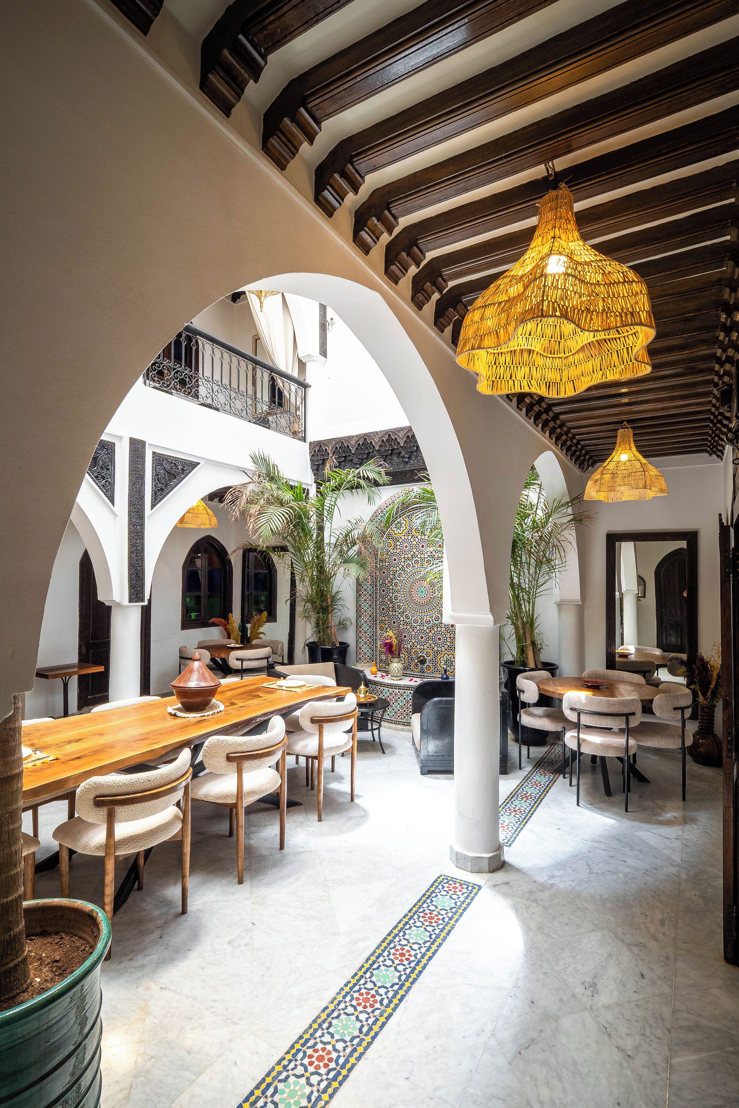 A spacious interior with high ceilings, arched doorways, and a central open area with tables and chairs.