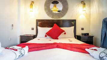 A hotel room with a large bed, two bedside tables, a wall-mounted mirror, and two wall sconces.
