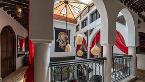 A multi-level interior with ornate railings, a tiled floor, and hanging decorative elements. - Riad Balkisse (Marrakech)
