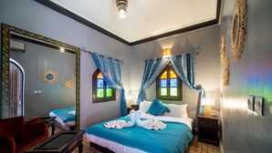 A hotel room with a large bed, two bedside tables, a red sofa, and a small table. - Riad Balkisse (Marrakech)