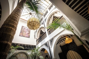 Un intérieur caractérisé par un plafond haut, des arches et des lampes suspendues.