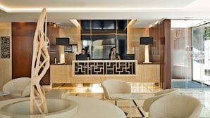 A modern reception area with a wooden reception desk, two receptionists, and a large glass window.