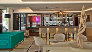 A modern bar area with a variety of liquor bottles, a large flat-screen TV, and contemporary bar stools.