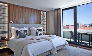 Quarto de hotel moderno com duas camas, uma janela grande e vista para a cidade.