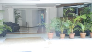 A modern lobby with a black leather sofa, a reception desk, and several potted plants. - Hotel Executive Residency (Pune)