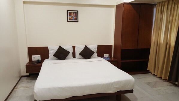 A hotel room with a bed, a nightstand, a wardrobe, and a picture on the wall. - Hotel Executive Residency (Pune)