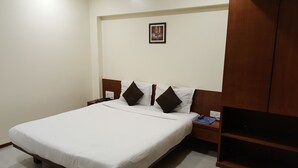 A hotel room with a large bed, two nightstands, a small framed picture on the wall, and a wooden wardrobe. - Hotel Executive Residency (Pune)