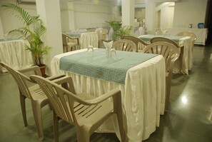 A dining area with tables covered in checkered tablecloths, surrounded by plastic chairs. - Hotel Executive Residency (Pune)