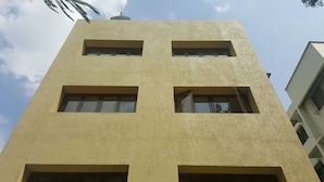 A building with a textured facade, multiple windows, and a visible antenna on the roof. - Hotel Executive Residency (Pune)