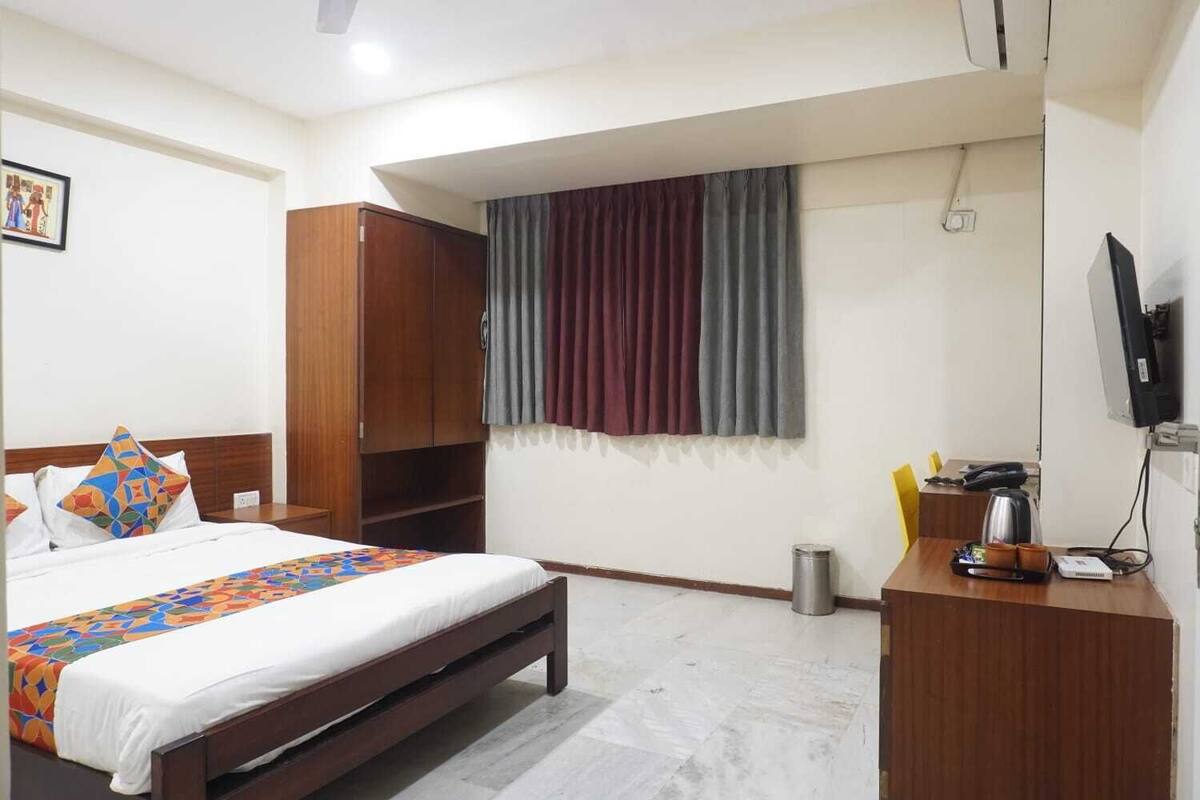 A hotel room with a bed, a desk, a television, and a wardrobe.