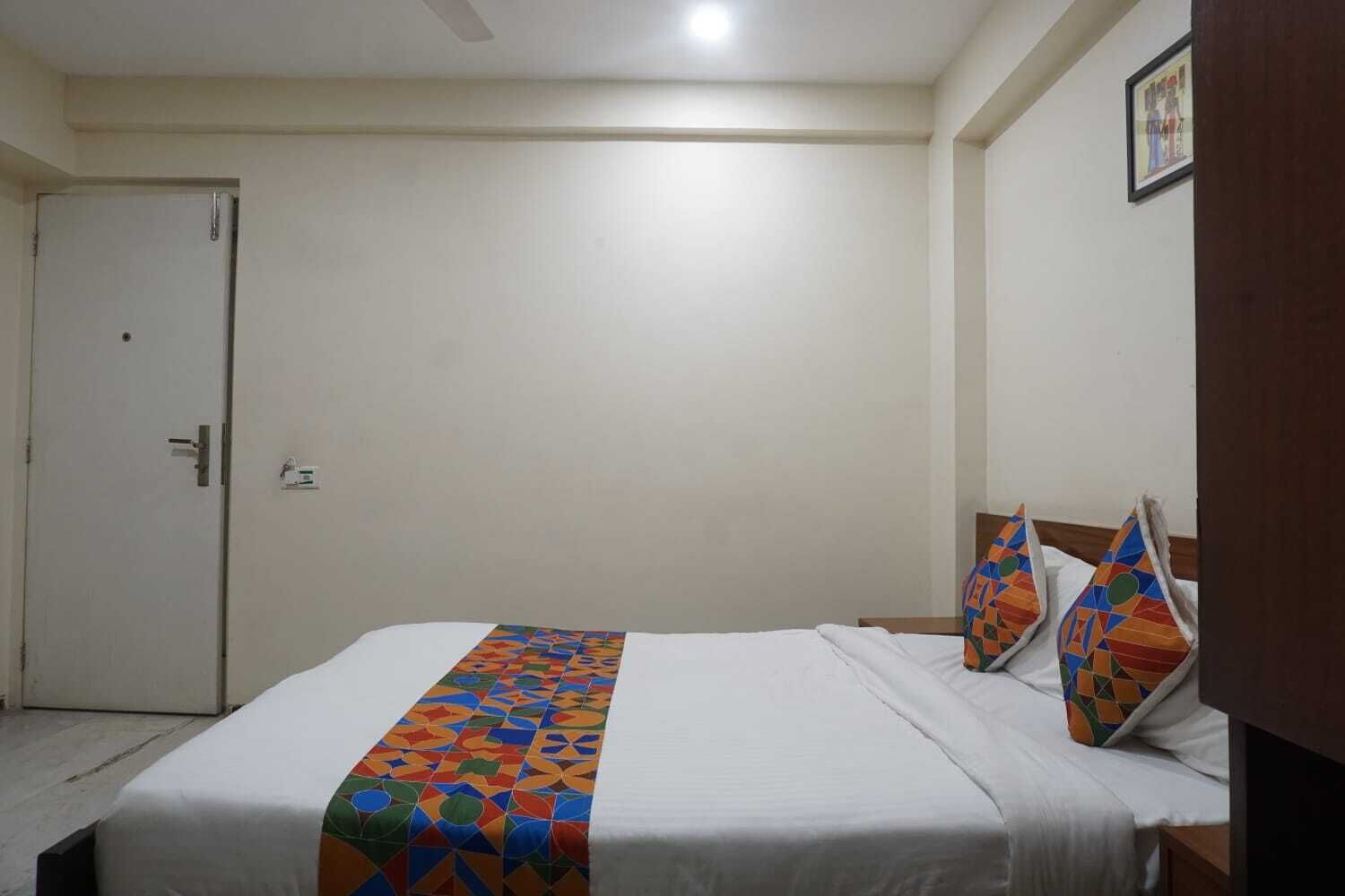 A hotel room with a bed, a door, and a nightstand.