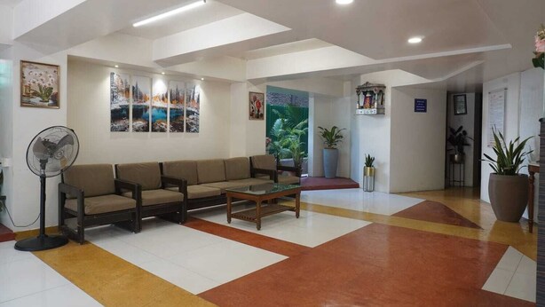 A spacious lobby with a sofa, a coffee table, and a fan. There are potted plants and artwork on the walls. - Hotel Executive Residency (Pune)