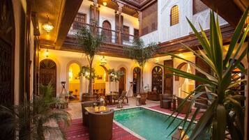 Un área de piscina interior lujosa con zona de estar, plantas en macetas y señalización de spa.