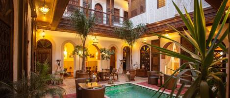A luxurious indoor pool area with a seating area, potted plants, and a spa sign.
