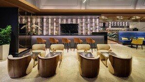 Zona de bar moderna con televisor, asientos y una vitrina para vinos.