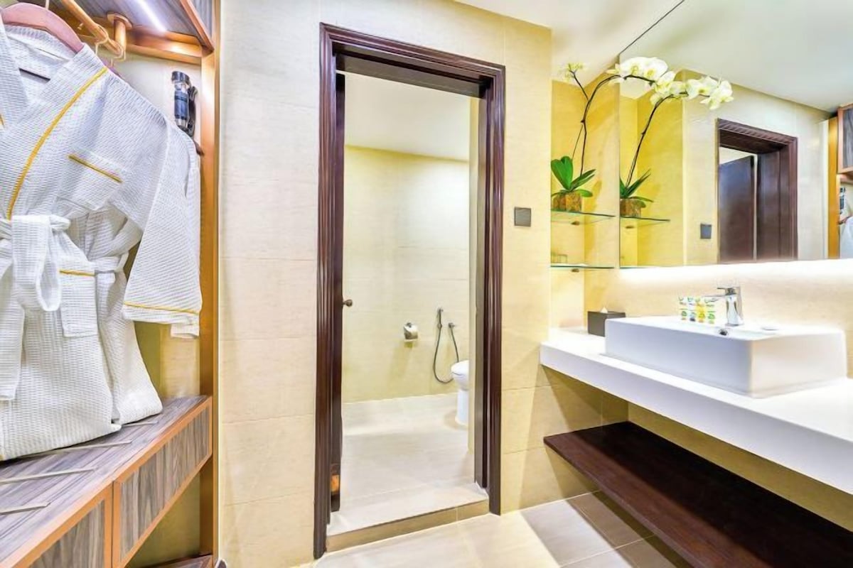 Un baño moderno con ducha a ras de suelo, un espejo grande y un lavamanos blanco.