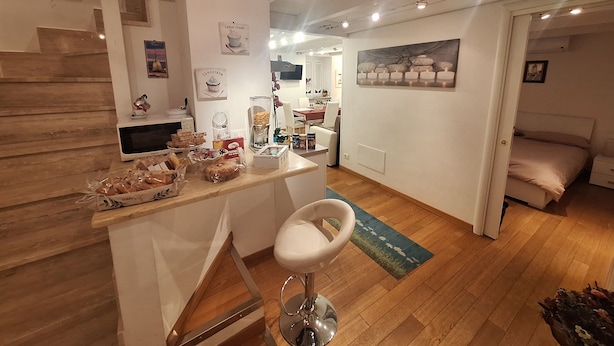 A modern kitchen with a central island, wooden flooring, and a dining area with a chair.