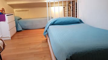 Cozy bedroom with two single beds, a dresser, and a table with a lamp.