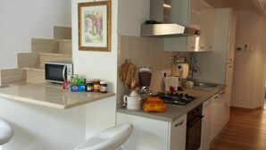 A compact kitchen with a microwave, stove, and various food items on the counter.