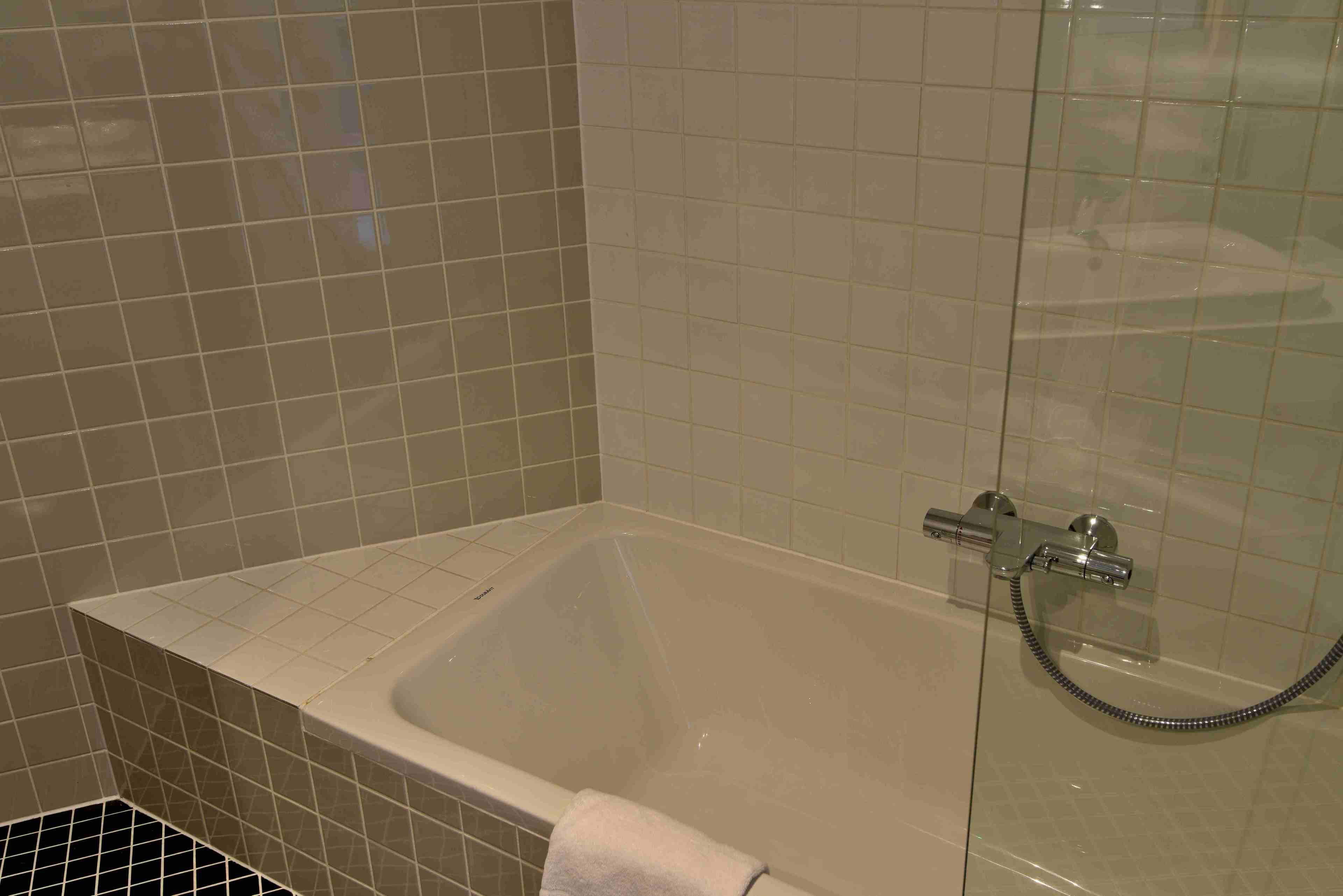 A bathroom with a bathtub, a glass shower enclosure, and tiled walls.