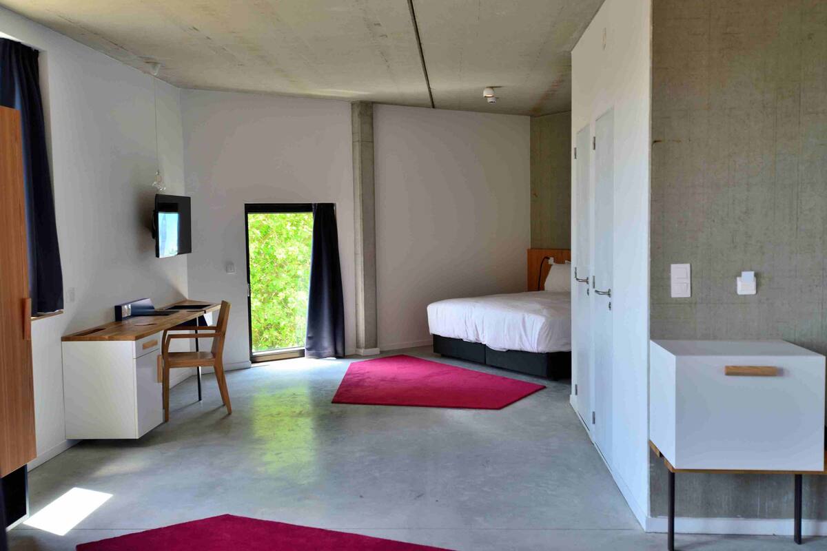 Ein modernes Schlafzimmer mit Schreibtisch, Bett und einem kleinen weißen Schrank.