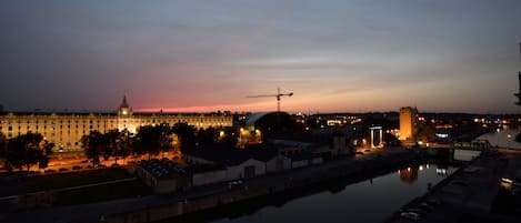 Ein nächtlicher Blick auf eine Stadtlandschaft mit einem markanten Gebäude mit Kuppel, einem Fluss und einer Brücke.