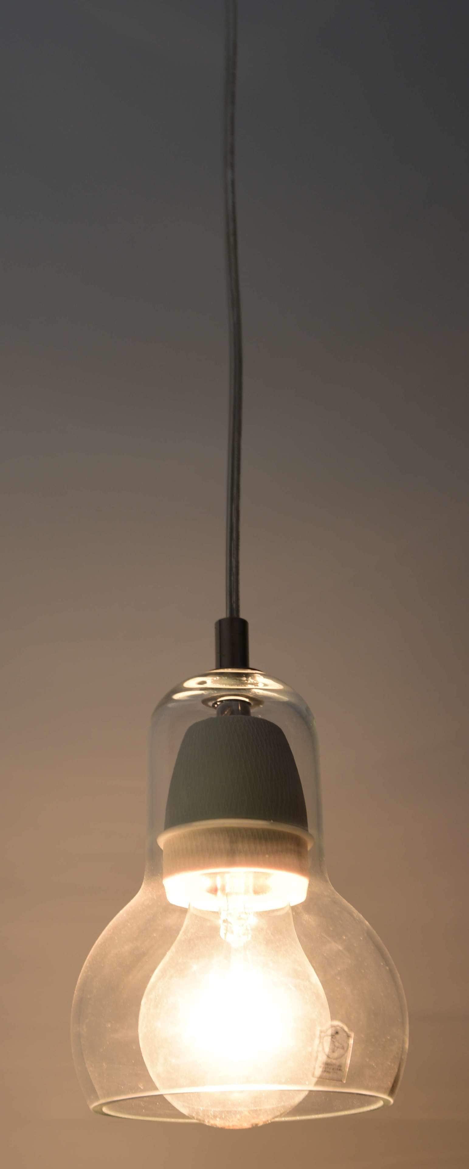 A pendant light fixture with a clear glass shade and a visible label.