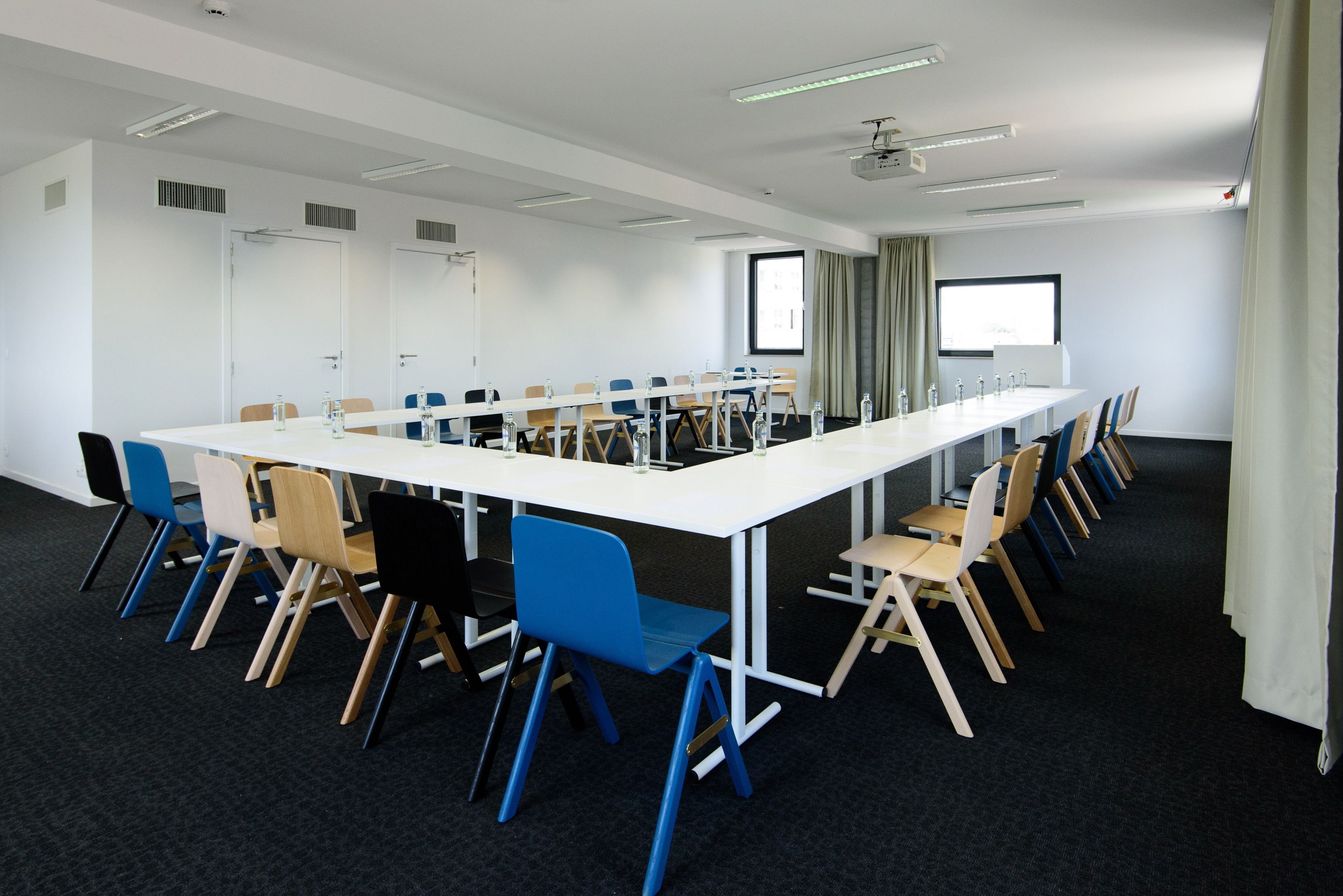 A conference room with a long table, multiple chairs, and a projector screen.