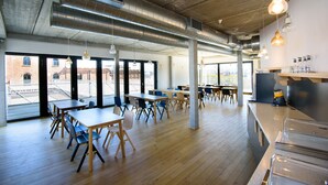 A spacious dining area with high ceilings, exposed ductwork, and large windows offering views of the city. - BELVUE Hotel (Brussels)