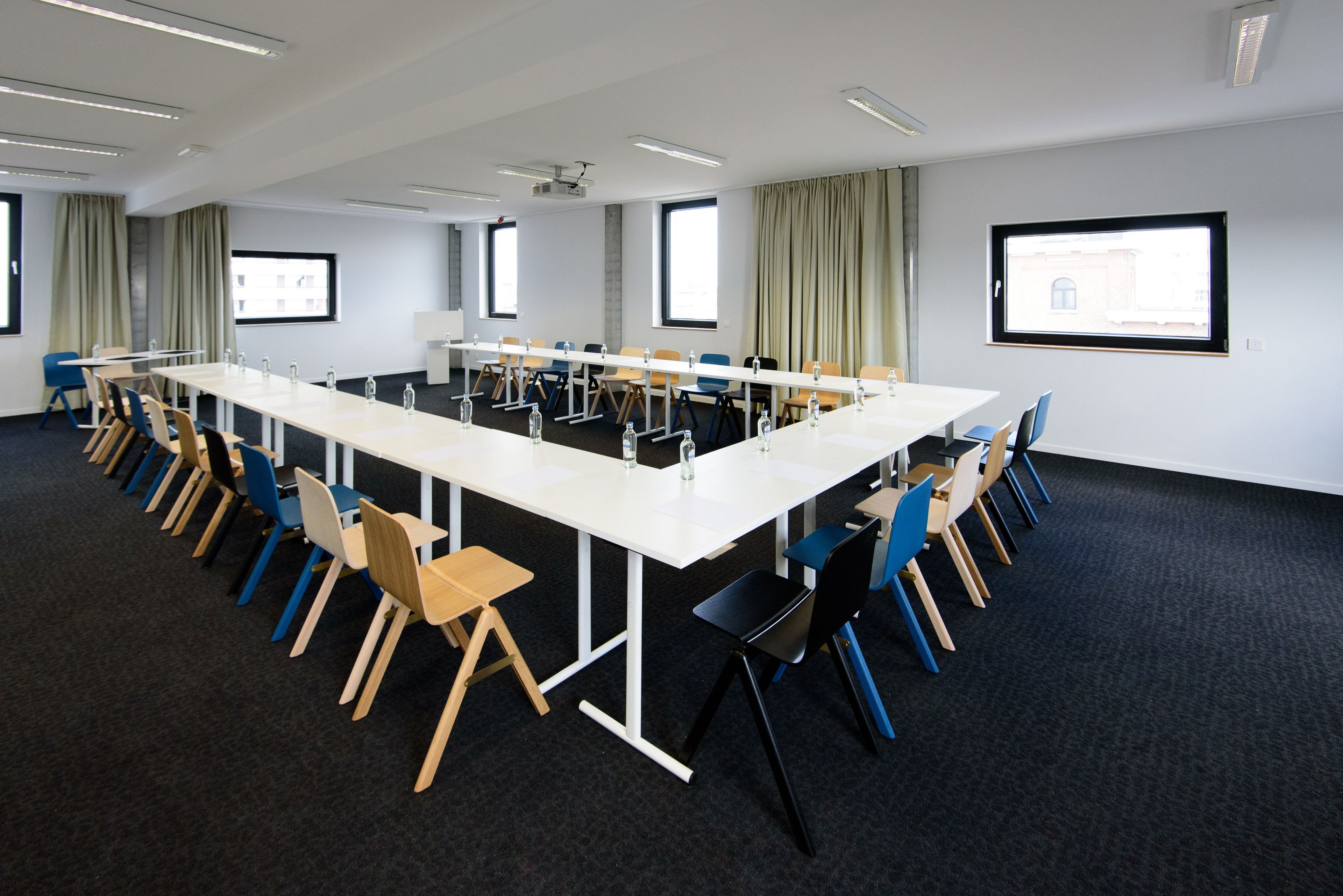 A conference room with a long table, chairs, and a projector screen.