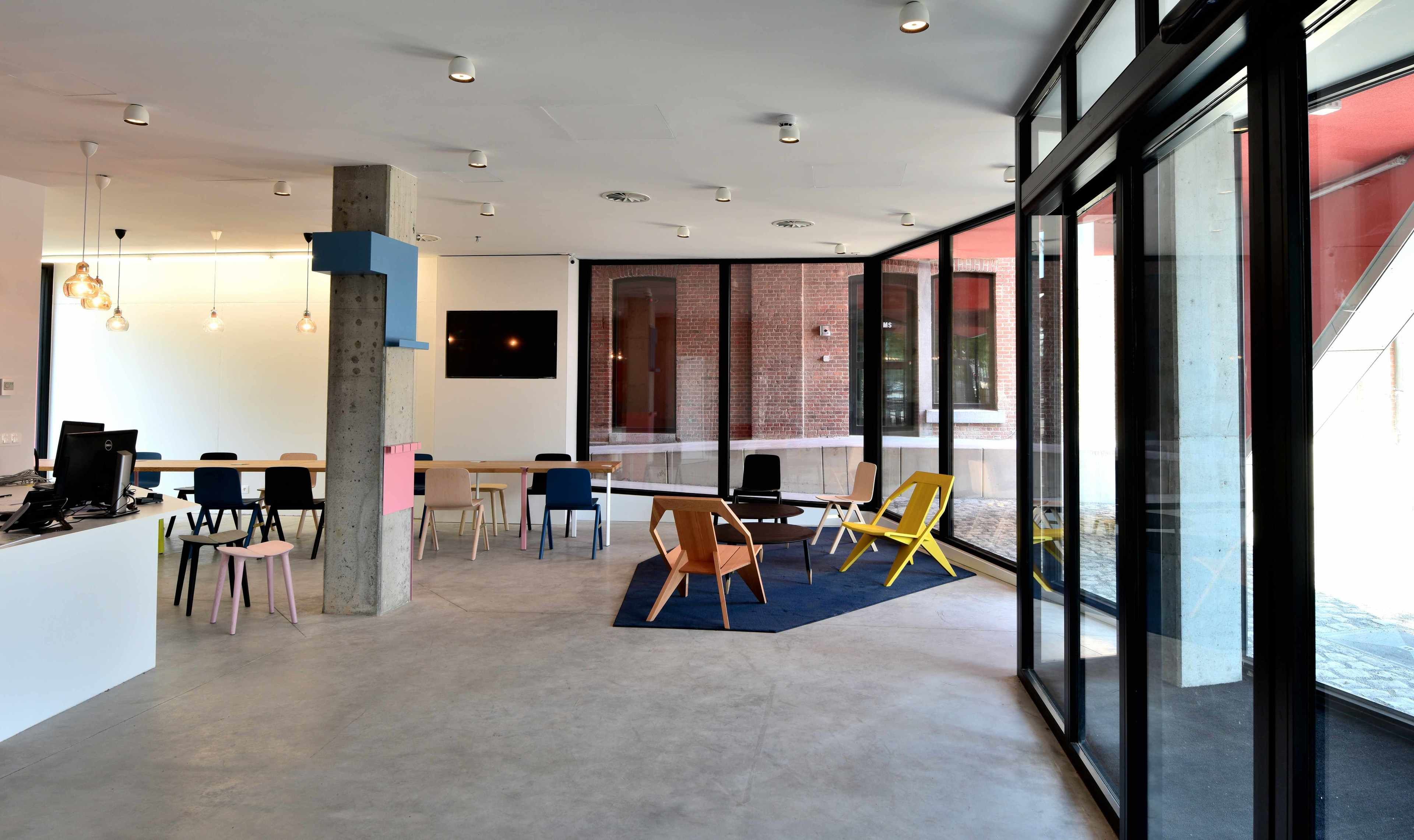 A modern office space with a large desk area, multiple chairs, and a large window offering a view of the street.