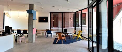 A modern office space with a large desk area, multiple chairs, and a large window offering a view of the street.