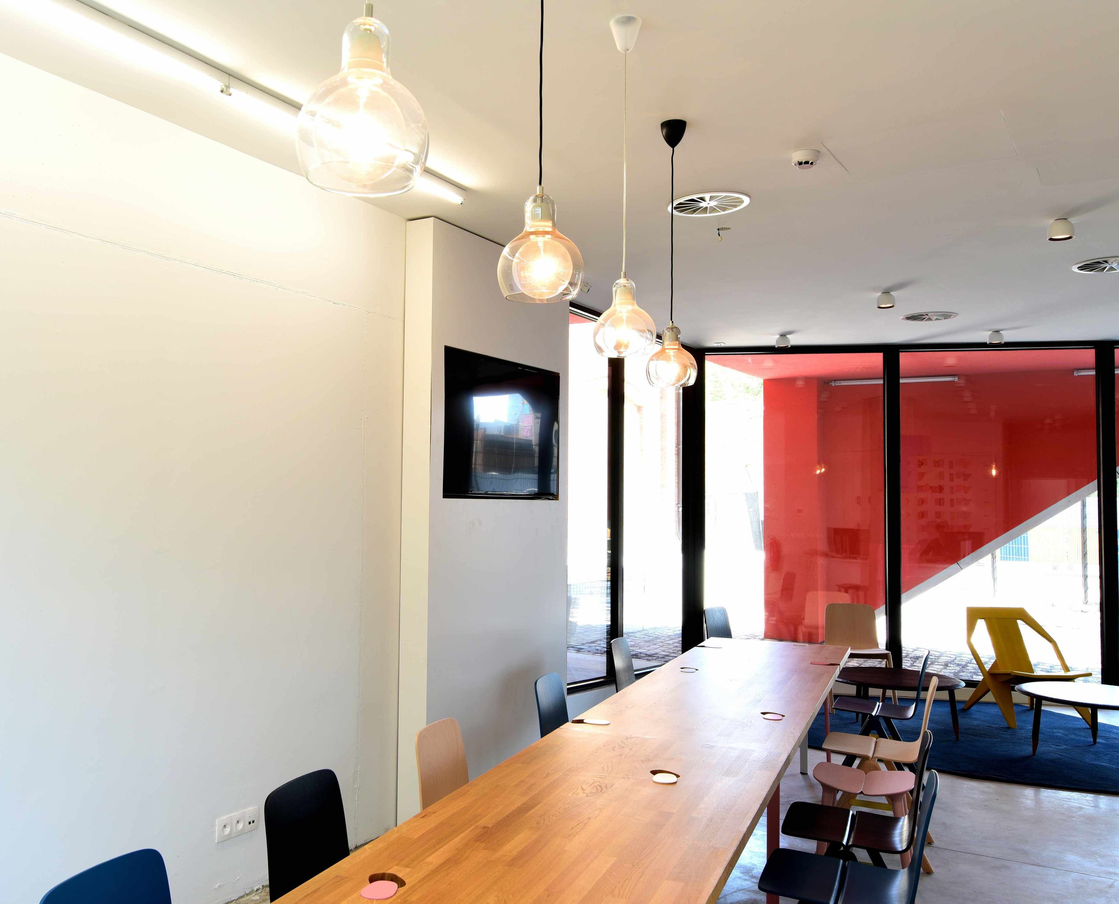 A conference room with a long wooden table, multiple chairs, and pendant lighting.