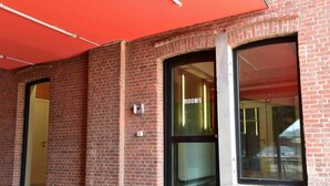 A brick building with a large glass door labeled "ROOMS" and a smaller door to the left. - BELVUE Hotel (Brussels)
