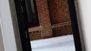 A doorway leading to a brick interior with a window and a red fire alarm. - BELVUE Hotel (Brussels)