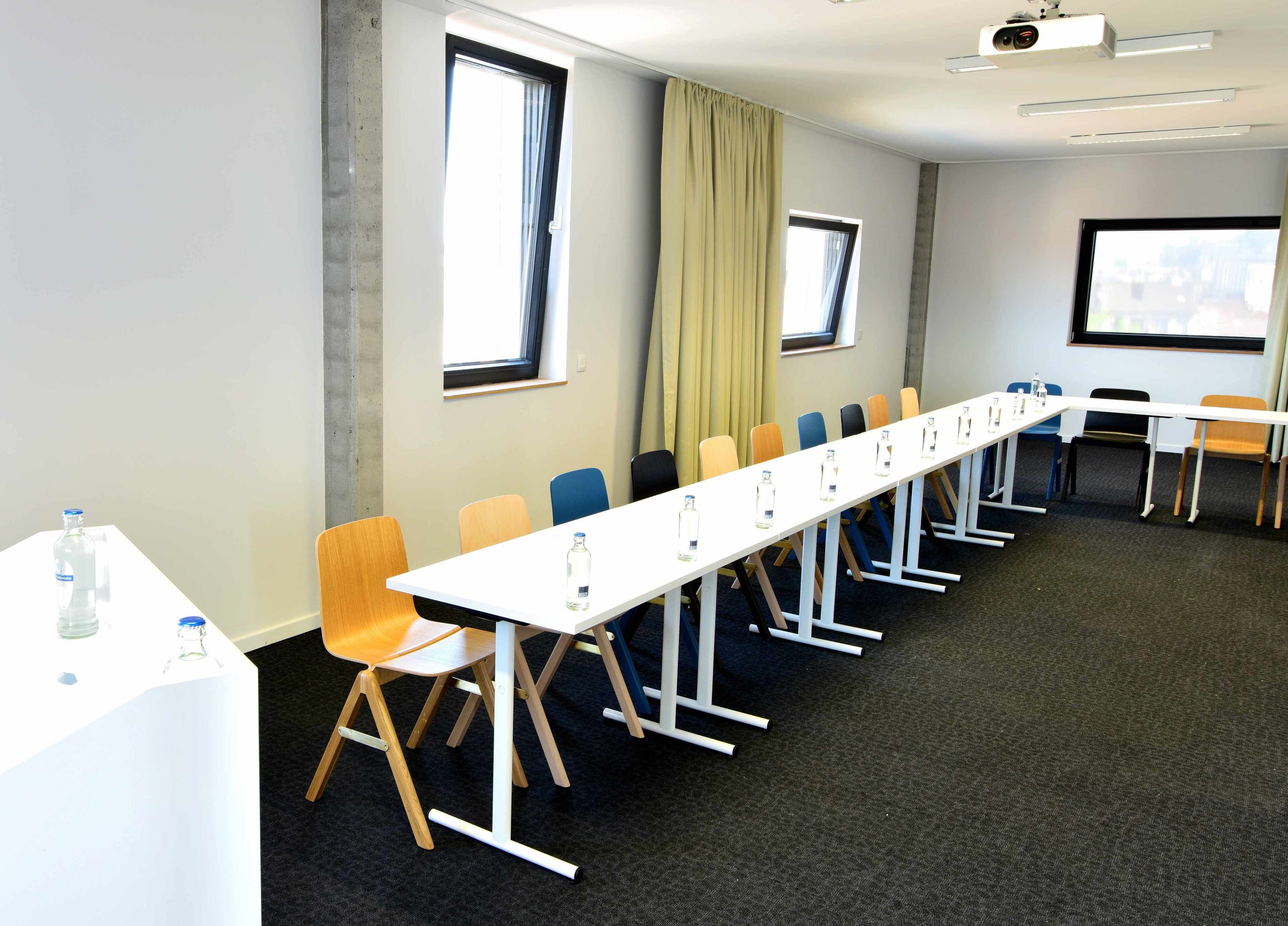 A conference room with a long table, chairs, and a projector.