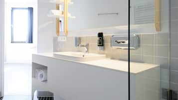 A modern bathroom with a large mirror, white vanity, and a glass shower enclosure.