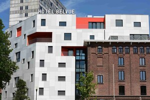 Et moderne hotel med en blanding af hvide og røde facader, flere vinduer og et tydeligt skilt med teksten "HOTEL BELVUE".
