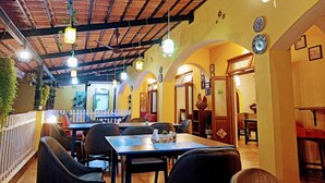 An indoor dining area with tables and chairs, wooden beams on the ceiling, and decorative lights. - Carina Beach Resort (Benaulim)
