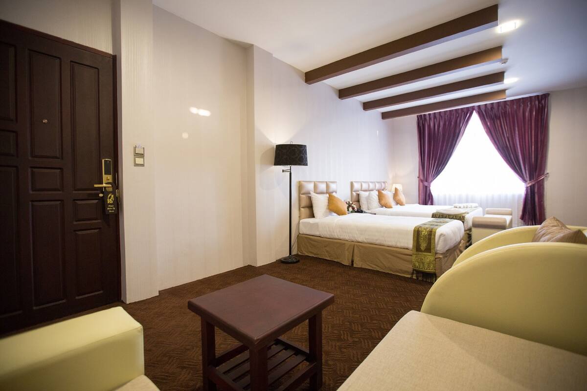 A hotel room with a large bed, a smaller bed, a desk, and a chair.