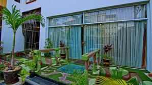 A modern building with large windows, a small garden area with a fountain, and outdoor seating. - Rising Venus Hotel (Mandalay)