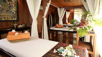 A room with a bed, a table with a vase of flowers, and a painting on the wall.