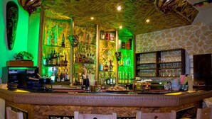 A bar area with a stone wall, wooden bar counter, and bar stools.
