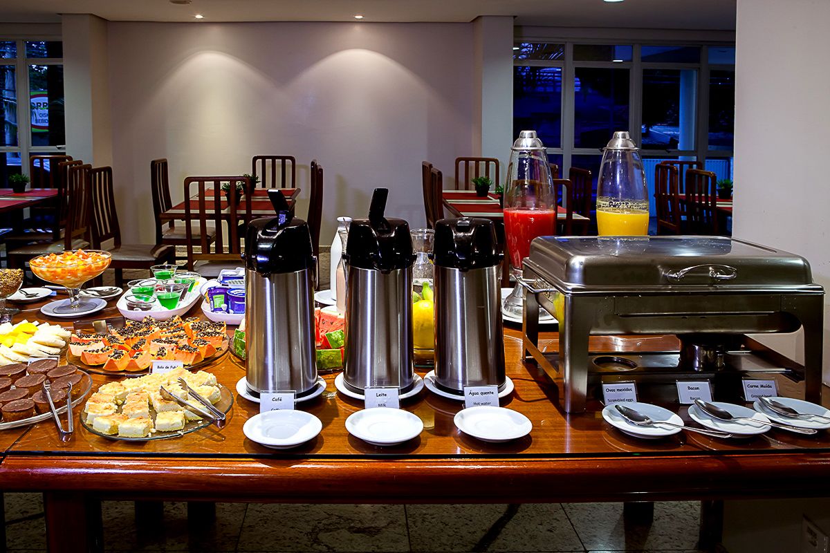 Montaje de bufé con diversas opciones de comida y bebidas, incluyendo agua caliente, jugo y una estación de café.