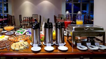 Montaje de bufé con diversas opciones de comida y bebidas, incluyendo agua caliente, jugo y una estación de café.